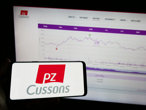 Stuttgart, Germany - 04-20-2023: Person holding mobile phone with logo of British consumer goods company PZ Cussons plc on screen in front of web page. Focus on phone display.