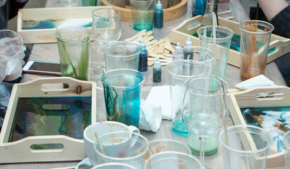 workshop on painting wooden pallets with epoxy resin. Plastic cups with colored resin, on the table, close-up. Painstaking work with gloves. Hobbies, entertainment