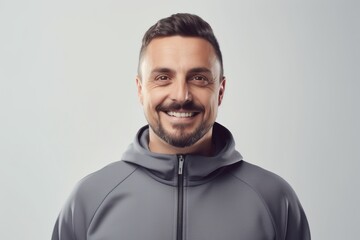 Obraz premium Portrait of handsome young man in hoodie looking at camera and smiling while standing against grey background