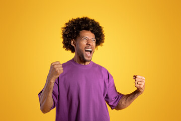 Excited excited adult african american curly man in purple t-shirt with open mouth shouting,...