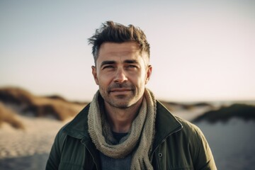 Portrait of a handsome young man with a beard in a green jacket on the beach
