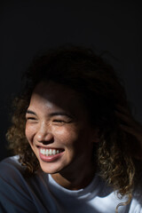 Smiling woman with curly hair and freckles on her face.