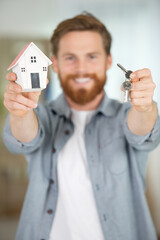handsome man holding model house and keys in hands