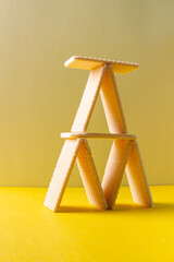 Wafer vanilla cookies making a tower of card with yellow background
