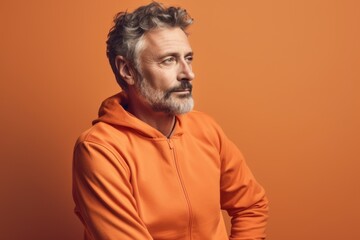 Fototapeta premium Portrait of a senior man in an orange hoodie on a orange background.
