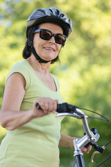 Naklejka premium senior female cyclist wearing helmet and sunglasses