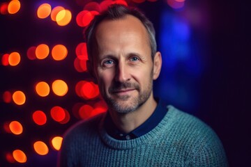 Portrait of a handsome man in a blue sweater on a background of Christmas lights.