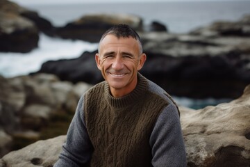 Portrait of smiling mature man standing on rock by sea at the beach