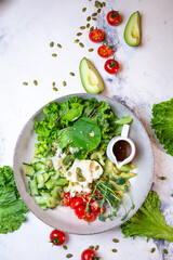 vegetarian salad with broccoli, tomato and herbs with sauce on a plate top view