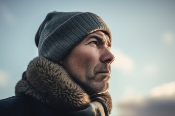 Portrait of a man in a winter hat and coat looking away.