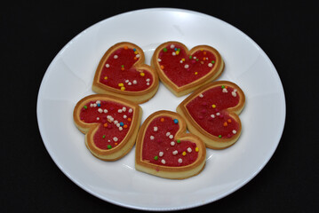 Red heart cookies on a white plate. Sweet cookies with a heart.