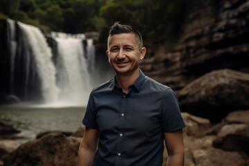 Lifestyle portrait photography of a grinning man in his 30s wearing a sporty polo shirt against a waterfall background. Generative AI