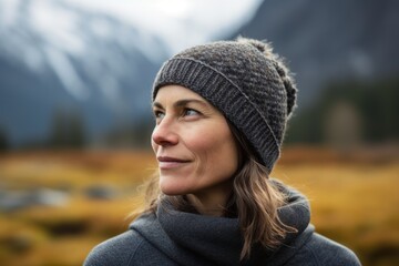 Portrait of a beautiful woman wearing a hat and coat looking away in the mountains