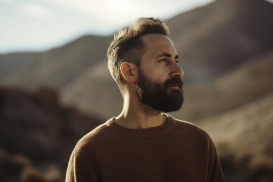 Portrait of a handsome bearded man in a brown sweater on a mountain background