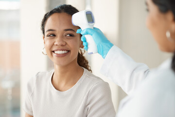 You have a very normal temperature. a young woman sitting in the clinic and getting her temperature checked by her doctor during a consultation.