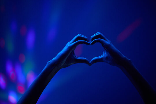 Weve got nothing but love. an unrecognisable couple making a heart shaped gesture while at a concert.