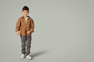 Cheerful cute little child 6 years old in casual walking with free space, isolated on gray studio background