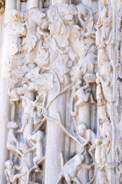 Marble details on facade of Messina Cathedral or Duomo di Messina, Sicily, Italy. Reliefs on wall picturing human figures harvesting grapes. Decorative elements in architecture
