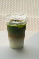 side view matcha green tea coffee in plastic glass on white floor, white wall background, food, drink, banner, template, copy space