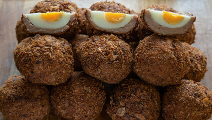 Scotch eggs on a wooden chopping board display regimentally.