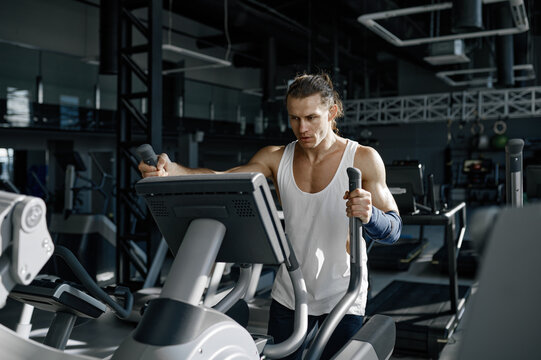 Sweaty sportsman doing cardio exercise on orbitrack training apparatus