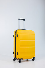 Yellow plastic strong suitcase for carrying luggage on a white background. A bright suitcase for travel