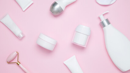 Cosmetic beauty products on pink background. Bottles and tubes with branding mock up. Skin care and beauty concept. Top view, flat lay, banner