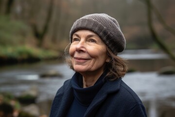 Portrait of a smiling senior woman in winter clothes standing by the river