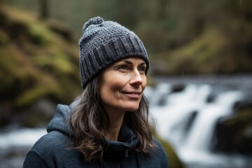 Portrait of a smiling woman standing in front of a waterfall in the forest