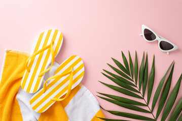 Chic summer vacation concept. Top view flat lay of yellow striped flip-flops, towel, green palm leaves, vintage sunglasses on pastel pink background