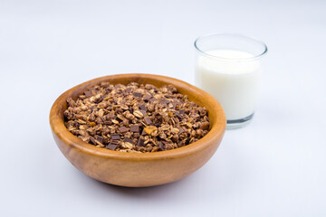 Chocolate granola with milk in wooden bowl 