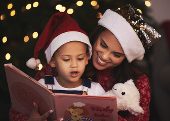 Shes getting better by the day. a young mother and daughter reading a book during Christmas time at...