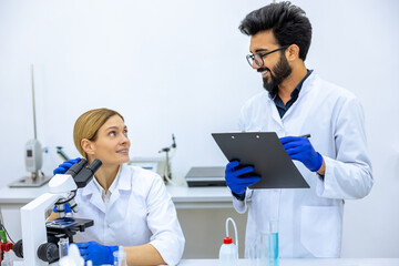 Woman and man scientists in lab coat making notes after doing sample test in laboratory.