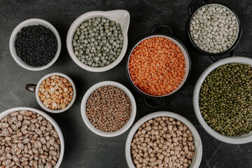 Many bowls of various legumes.Dark background.Top view