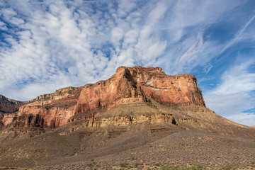 Scenic view on massive mesa cliff The Battleship seen from Bright Angel and Plateau Point hiking trail, South Rim of Grand Canyon National Park, Arizona, USA. Barren terrain in Southwest with blue sky