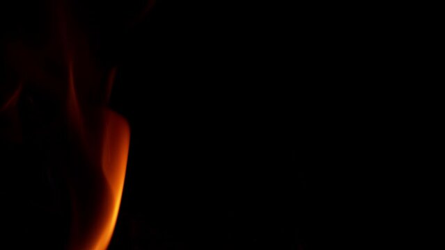 Flames on black background. Small flames from the bottom of the frame. 4k 50fps. Layer for fire and flame effect. Heat, bonfire and light in the dark. Flare, splashes, light effects, graphic material.