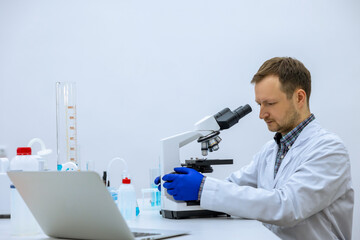 Scientist man doing chemical experiment, making analyzing, looking sample under microscope