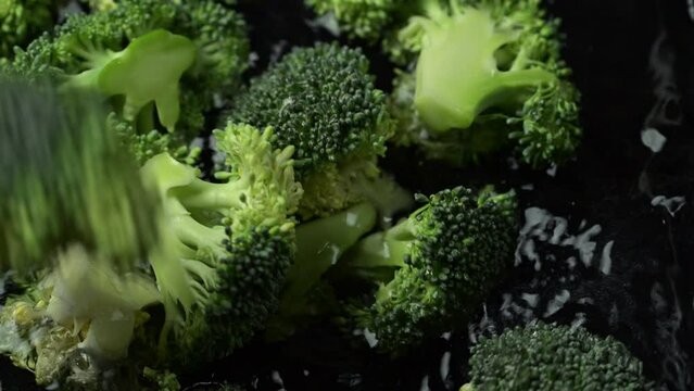 Broccoli slices falling in water. Fresh organic broccoli cabbage with water drops.