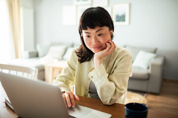 Young Japanese Woman working on a laptop in the kitchen