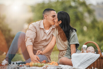 Your kisses make my heart flutter. a young couple kissing during a picnic.