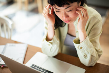 Young Japanese Woman working on a laptop in the kitchen