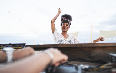 Cheerful african girl with pretty smile dancing on the beach during party while the Dj playing...