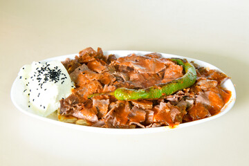 Traditional turkish iskender kebab in copper plate with yogurt, grilled tomatoes and fresh vegetables.
