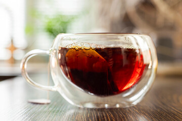 A hot cup of freshly brewed black tea with steam on wooden table