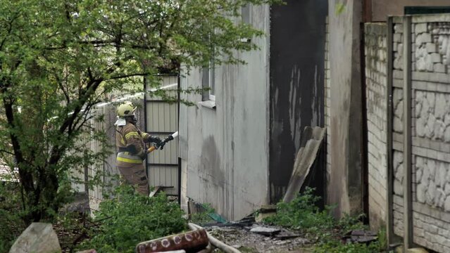 Firefighters extinguish a private house from fire hoses with water during a fire.