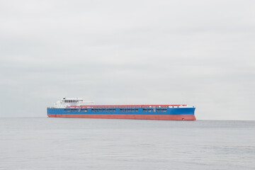 loaded cargo ship at sea under cloudy gray sky