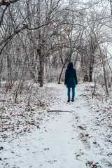 A woman walks through a snowy forest in winter