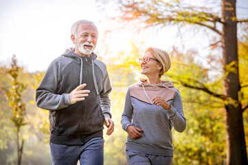 Smiling senior couple jogging in the park. Sports activities for elderly people
