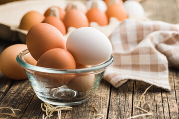 Whole chicken eggs in bowl on wooden table.