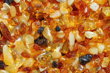 Amber texture background, small stones yellow orange gradient color. Natural gemstone mineral for jewelry. Top view Amber textured fon. Sunstones pieces ancient resin. Transparent pieces gem.
